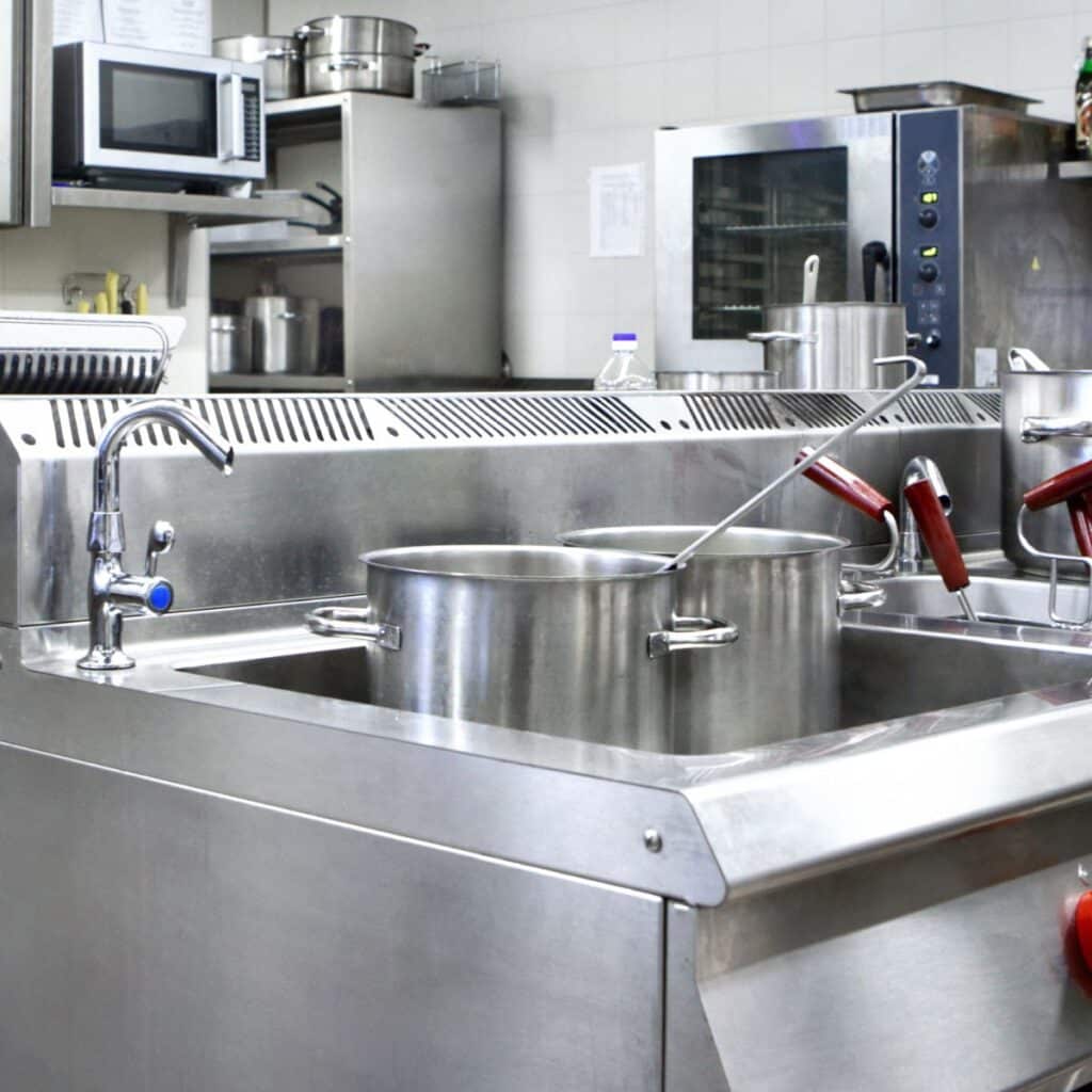 industrial kitchen sink with large pots and pans sitting in it