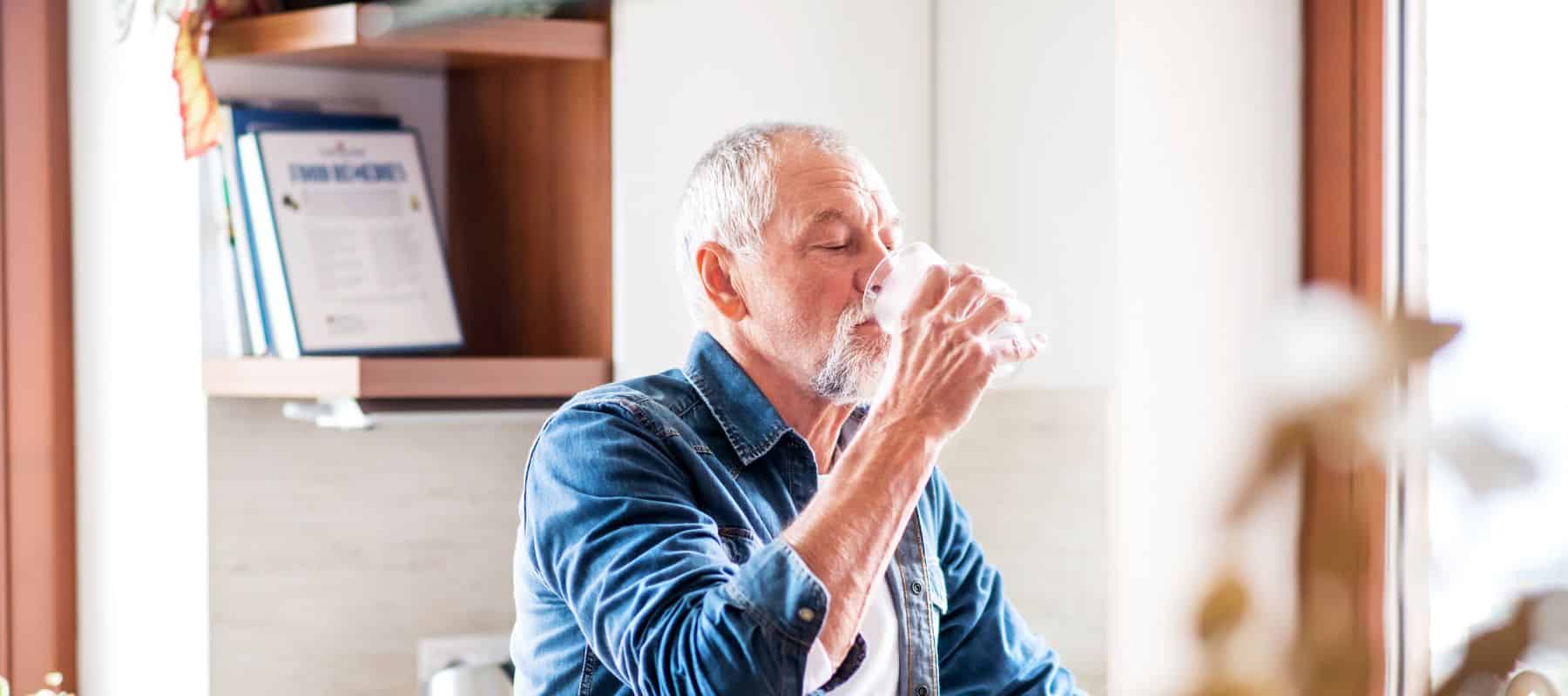 older gentleman drinking water from a glass